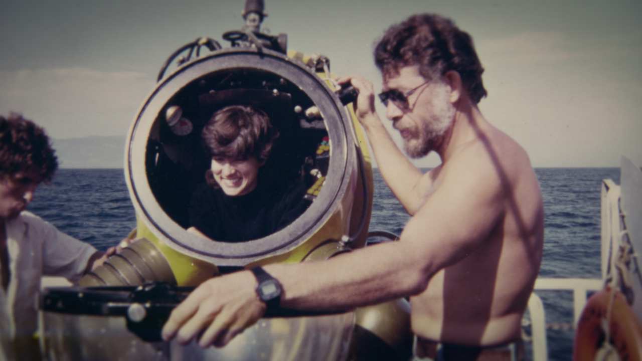 two men and a woman in a vintage diving suit